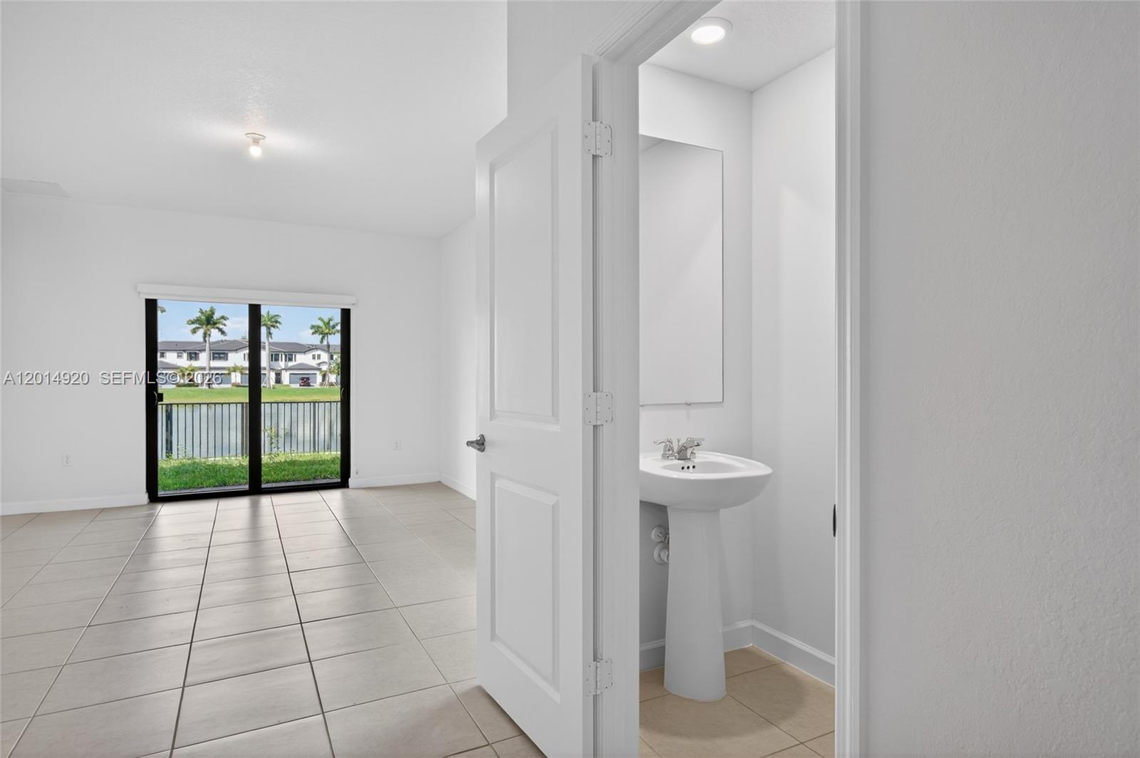 A small powder room features a white pedestal sink and a wall-mounted mirror — 4981 Peacock Way, Dania Beach FL 33312, DANIA BEACH, FL