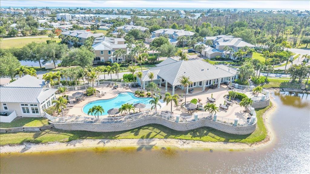 An aerial view shows a community clubhouse with a pool overlooking a lake — 8560 AMBERJACK CIRCLE UNIT 301, ENGLEWOOD, FL
