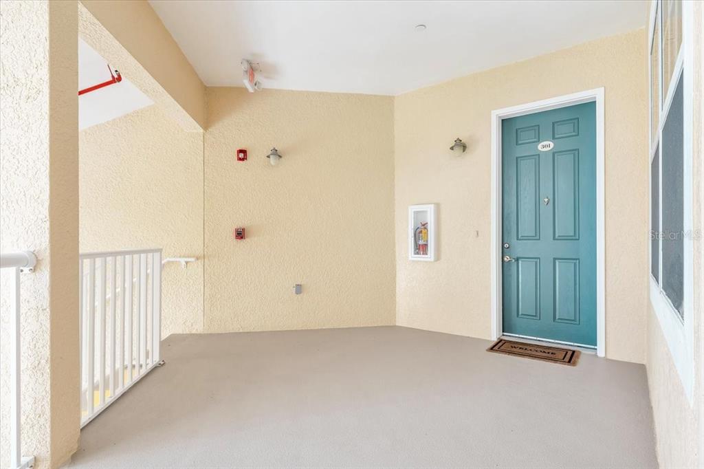 A teal front door with the number 301 is located on a covered outdoor balcony — 8560 AMBERJACK CIRCLE UNIT 301, ENGLEWOOD, FL