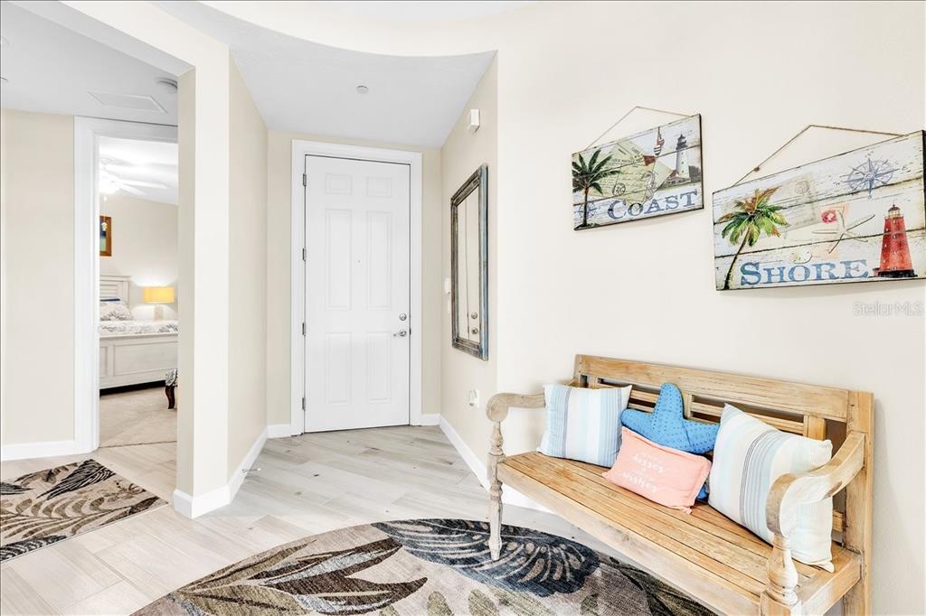 A coastal-themed entryway features a wooden bench, decorative wall signs, and light-colored tile flooring — 8560 AMBERJACK CIRCLE UNIT 301, ENGLEWOOD, FL