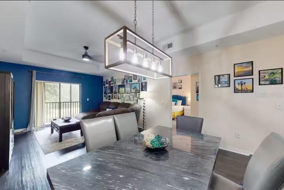 A dining area with a marble-topped table leads into a living room with blue walls — 9061 TREASURE TROVE LANE UNIT 204, KISSIMMEE, FL