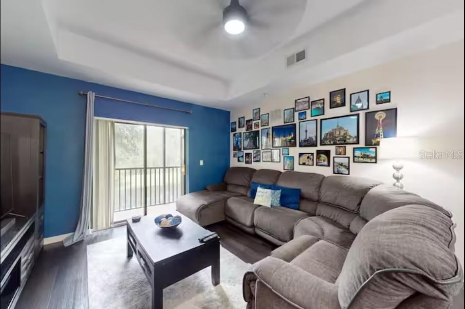 A living room features a blue accent wall, a large sectional sofa, and a gallery wall — 9061 TREASURE TROVE LANE UNIT 204, KISSIMMEE, FL