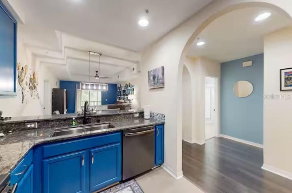 A kitchen with blue cabinets and granite countertops opens into a living area — 9061 TREASURE TROVE LANE UNIT 204, KISSIMMEE, FL
