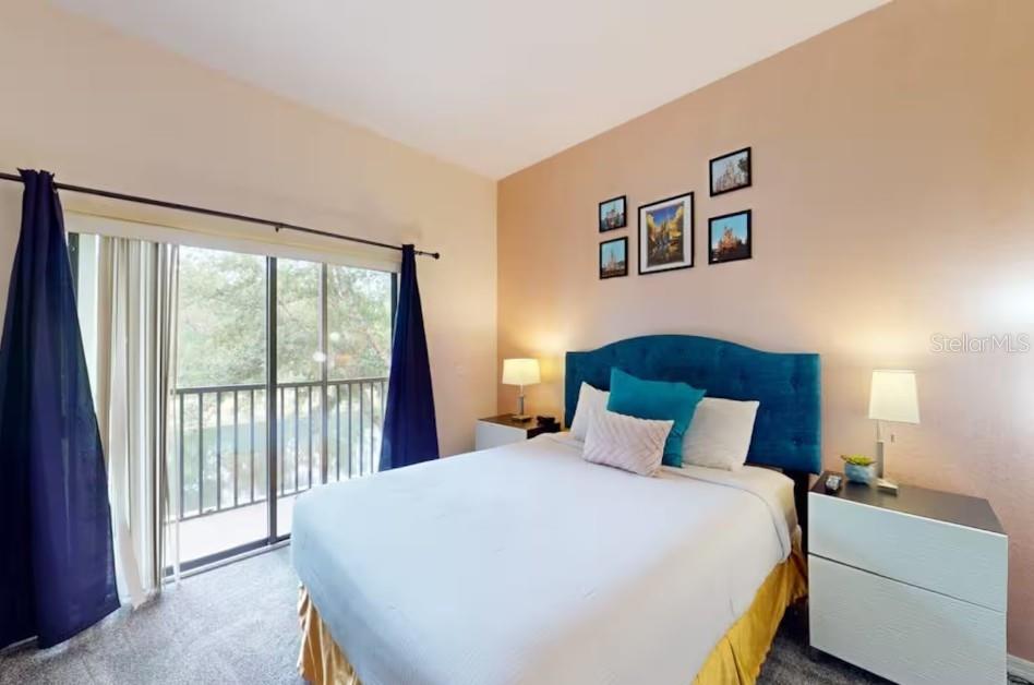 A bedroom features a blue headboard, a bed with a gold skirt, and a sliding door — 9061 TREASURE TROVE LANE UNIT 204, KISSIMMEE, FL