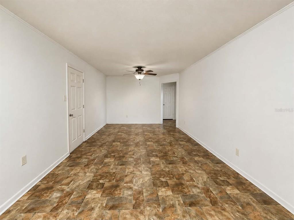 An empty room with white walls, a ceiling fan, and brown patterned tile flooring — 108 9TH ELOISE STREET, WINTER HAVEN, FL