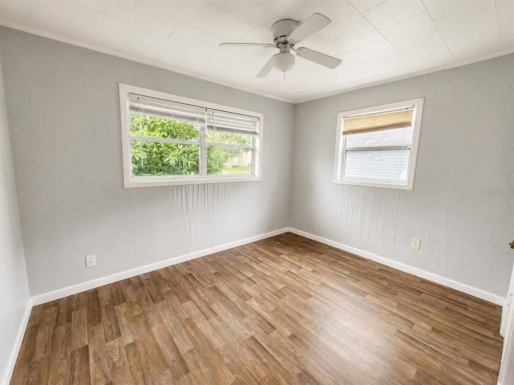 An empty bedroom features light gray walls, wood-look flooring, a ceiling fan, and two windows — 108 9TH ELOISE STREET, WINTER HAVEN, FL