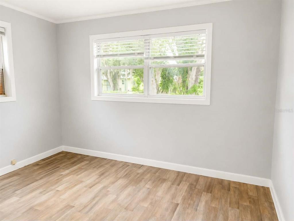 A bedroom with light gray walls, wood-look flooring, and a large window with white trim — 108 9TH ELOISE STREET, WINTER HAVEN, FL