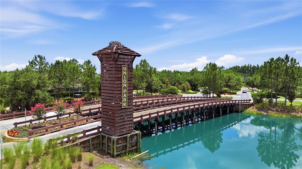 An elevated view of a wooden bridge with a tall tower sign over a pond — 32825 PEZ LANDING LANE, WESLEY CHAPEL, FL