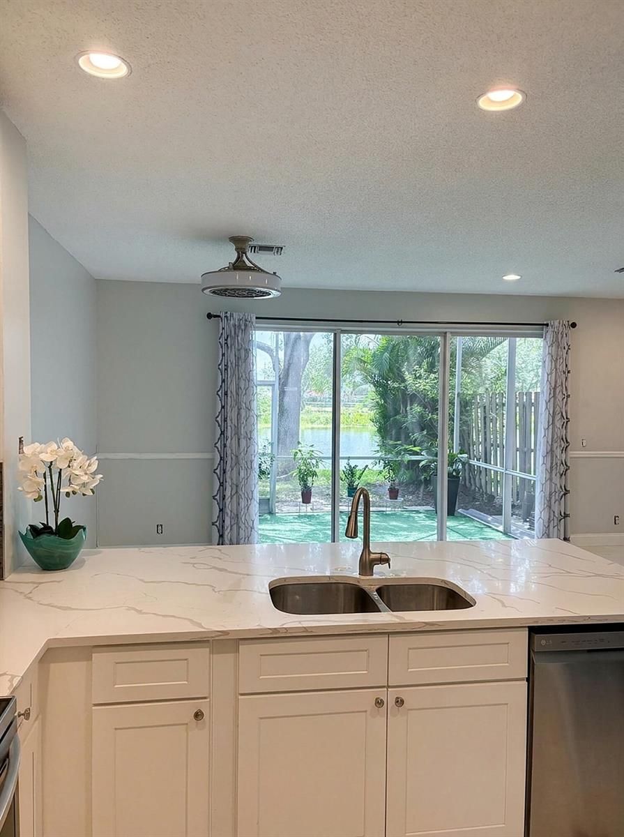 A kitchen island with a white marble countertop overlooks a sliding glass door to a patio — 7862 Sienna Springs Drive, Lake Worth FL 33463, LAKE WORTH, FL