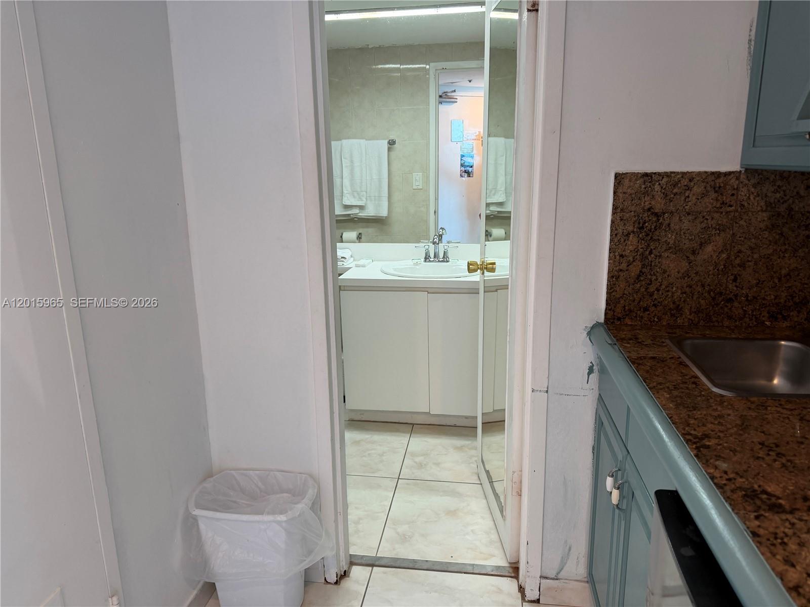 A view from a kitchen area looking into a bathroom with a white vanity — 5445 Collins Ave # 1606, Miami Beach FL 33140, MIAMI BEACH, FL
