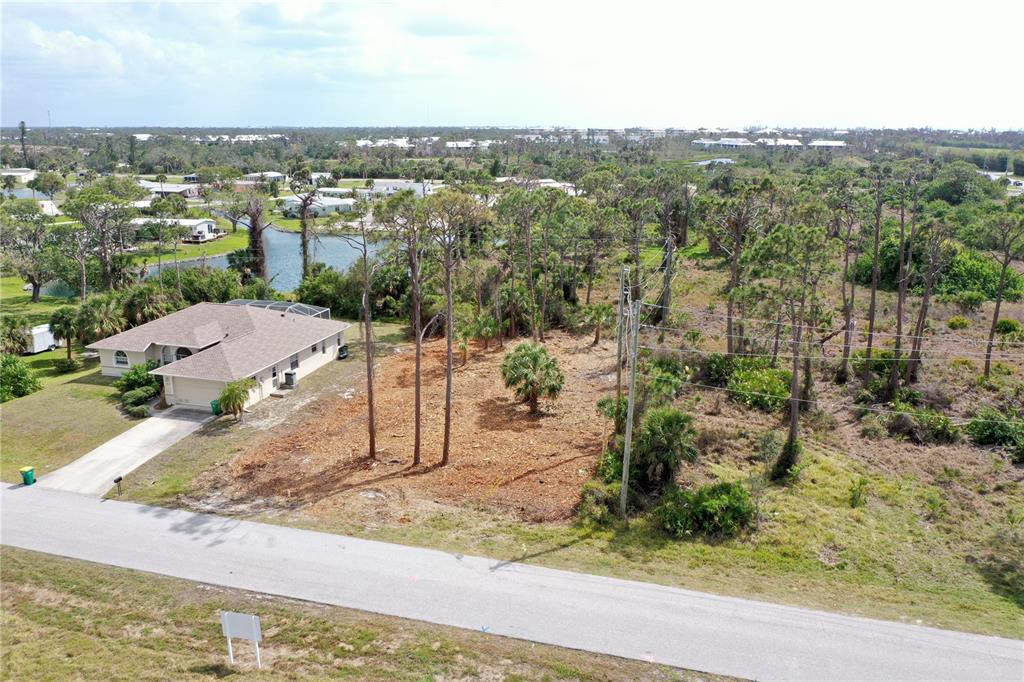 An aerial view shows a vacant lot next to a house with a paved road — 8905 BANTRY BAY, ENGLEWOOD, FL