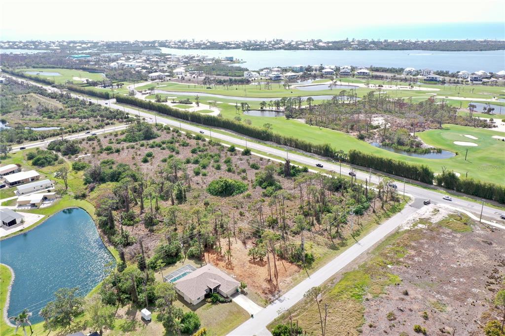 An aerial view shows a residential lot with a house, pond, and nearby golf course — 8905 BANTRY BAY, ENGLEWOOD, FL