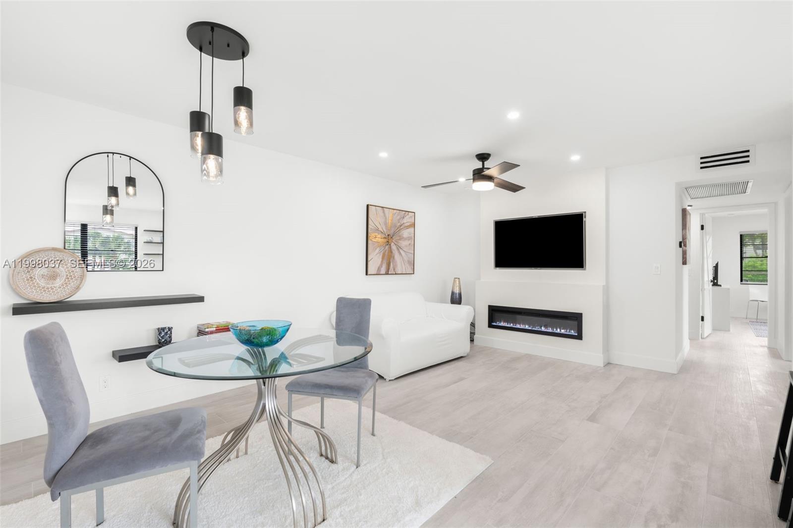A modern kitchen features white cabinetry, a marble-topped island with black stools, and large windows — 319 Preston H # 319, Boca Raton FL 33434, BOCA RATON, FL