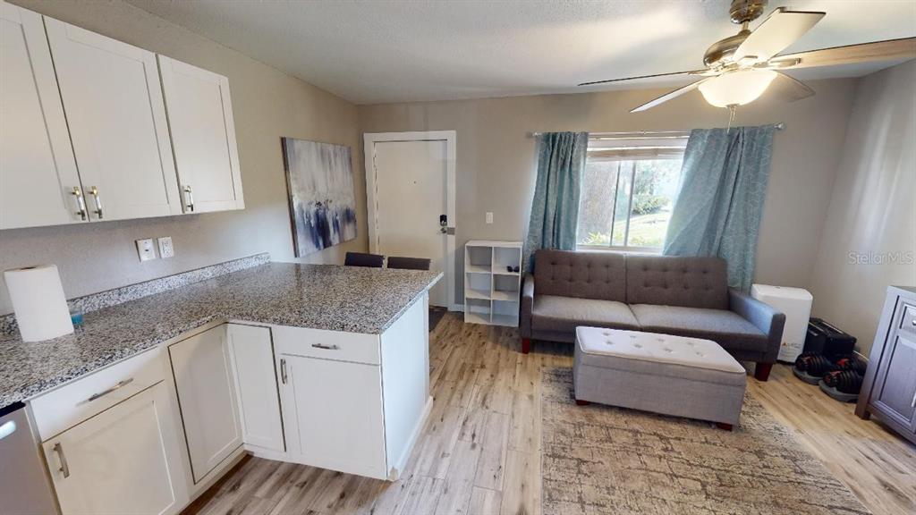 A kitchen with granite countertops opens into a living area with a gray sofa — 133 OYSTER BAY CIRCLE UNIT 100, ALTAMONTE SPRINGS, FL