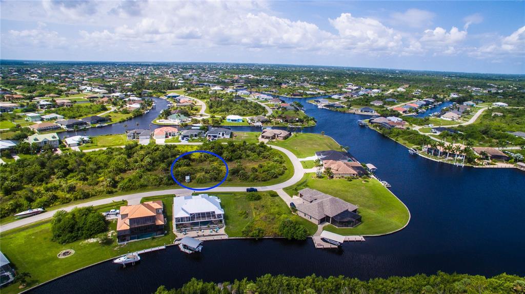 An aerial view shows a vacant, circular-highlighted lot surrounded by waterfront homes and canals — 15505 MARGO CIRCLE, PORT CHARLOTTE, FL