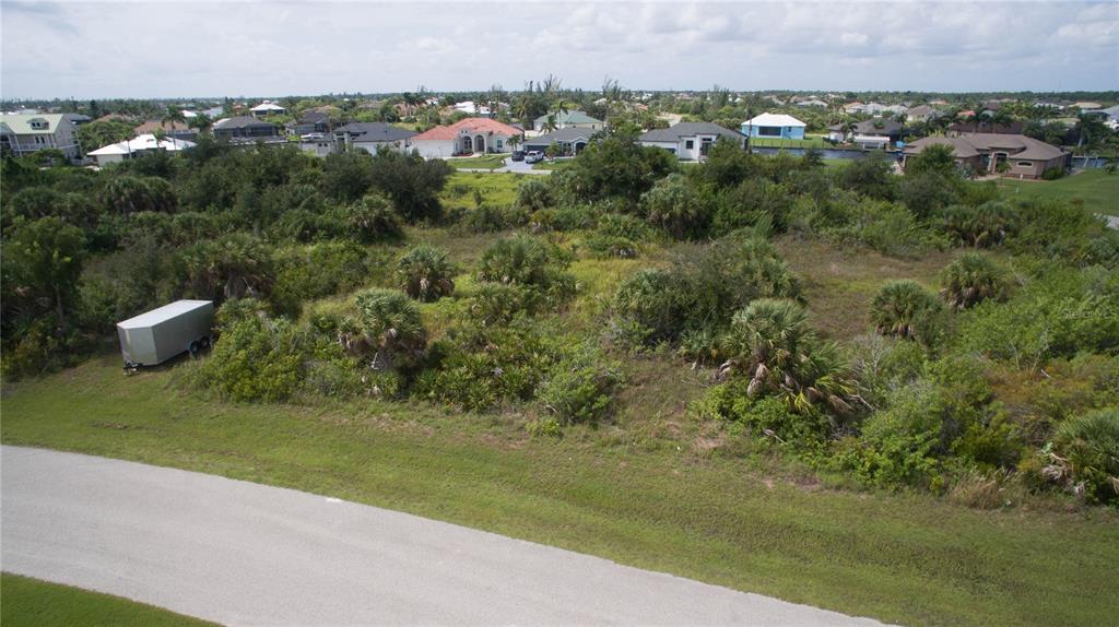 An aerial view shows a vacant, overgrown residential lot with a trailer parked on it — 15505 MARGO CIRCLE, PORT CHARLOTTE, FL