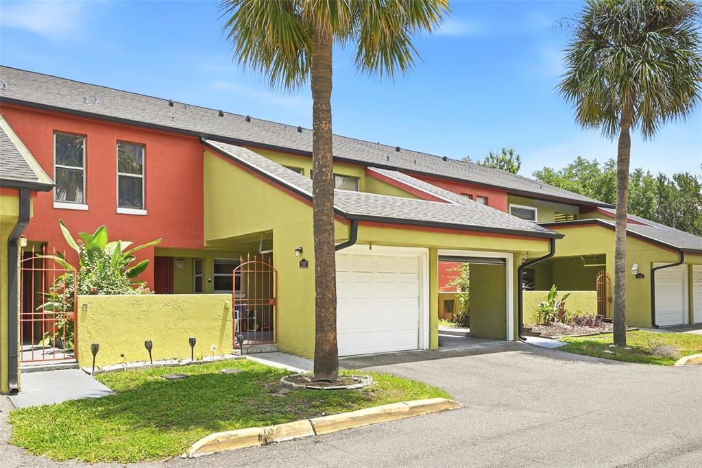 Exterior view of a multi-unit townhouse complex with lime green and orange stucco walls — 2107 HONOUR ROAD UNIT 2107, ORLANDO, FL