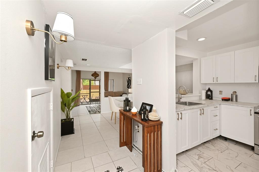 A kitchen with white cabinets and tile floors opens into a dining area and patio — 2107 HONOUR ROAD UNIT 2107, ORLANDO, FL