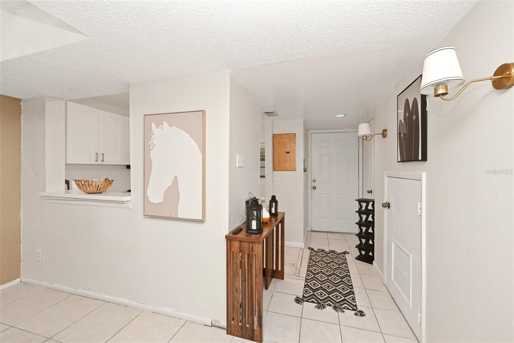 An entryway features white tile floors, a wooden console table, and a horse wall art piece — 2107 HONOUR ROAD UNIT 2107, ORLANDO, FL
