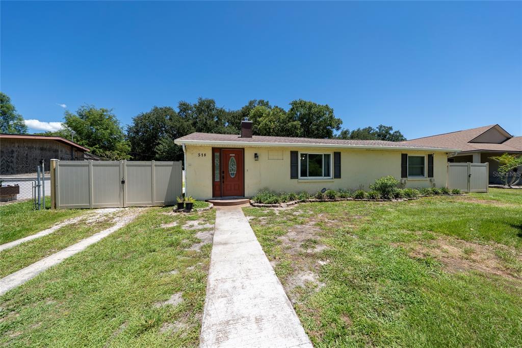 A single-story yellow house with a red front door and a concrete walkway — 518 TOHOPEKALIGA AVENUE, KISSIMMEE, FL