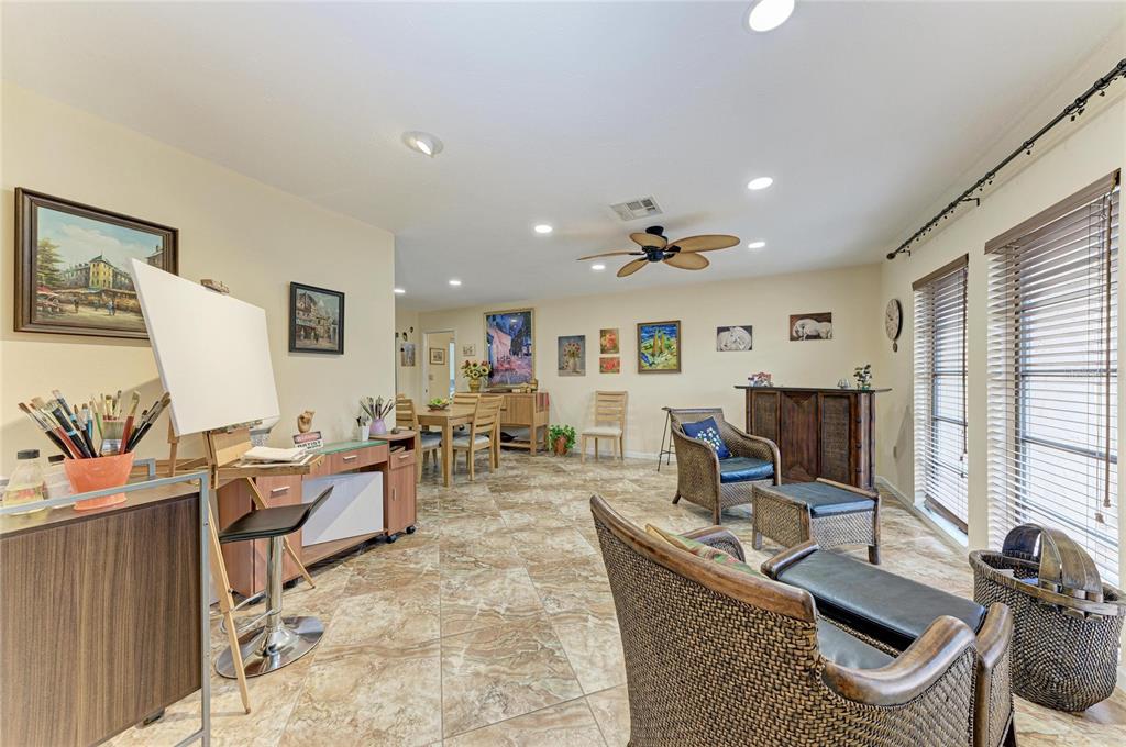A spacious room with tile flooring, an artist's easel, wicker chairs, and a dining area — 4533 KIPLING CIRCLE, SARASOTA, FL