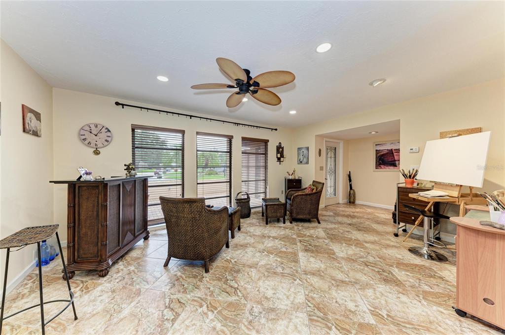A sunroom with tile flooring, a ceiling fan, wicker chairs, a bar, and an easel — 4533 KIPLING CIRCLE, SARASOTA, FL