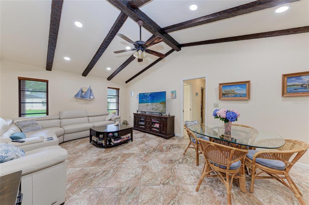 A living and dining area features vaulted ceilings with dark wood beams and tile flooring — 4533 KIPLING CIRCLE, SARASOTA, FL