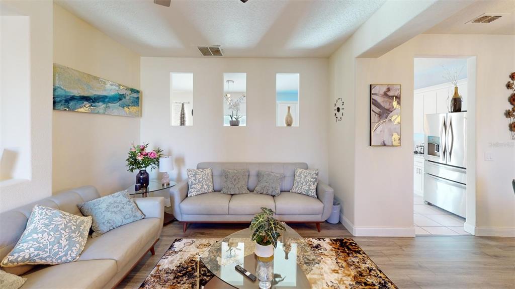 A living room features two gray sofas, a glass coffee table, and three wall niches — 3044 CAMINO REAL DRIVE S, KISSIMMEE, FL
