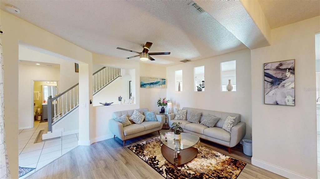 A living room features light gray sofas, a glass coffee table, and wood-look flooring — 3044 CAMINO REAL DRIVE S, KISSIMMEE, FL