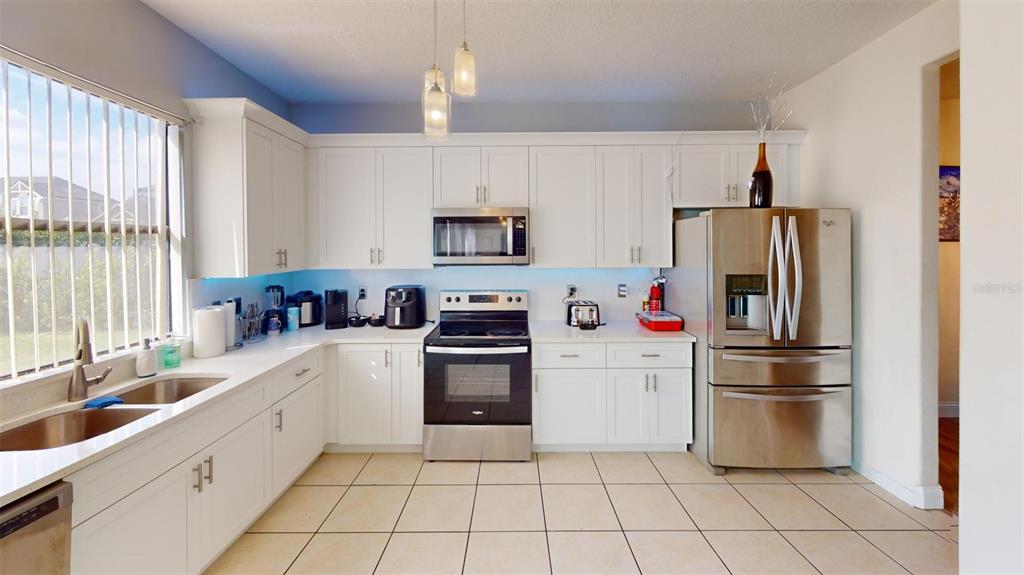 A kitchen with white cabinets, stainless steel appliances, and light-colored tile flooring — 3044 CAMINO REAL DRIVE S, KISSIMMEE, FL