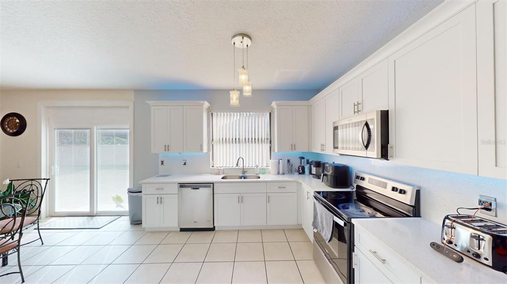 A kitchen with white cabinets, stainless steel appliances, and tile flooring — 3044 CAMINO REAL DRIVE S, KISSIMMEE, FL