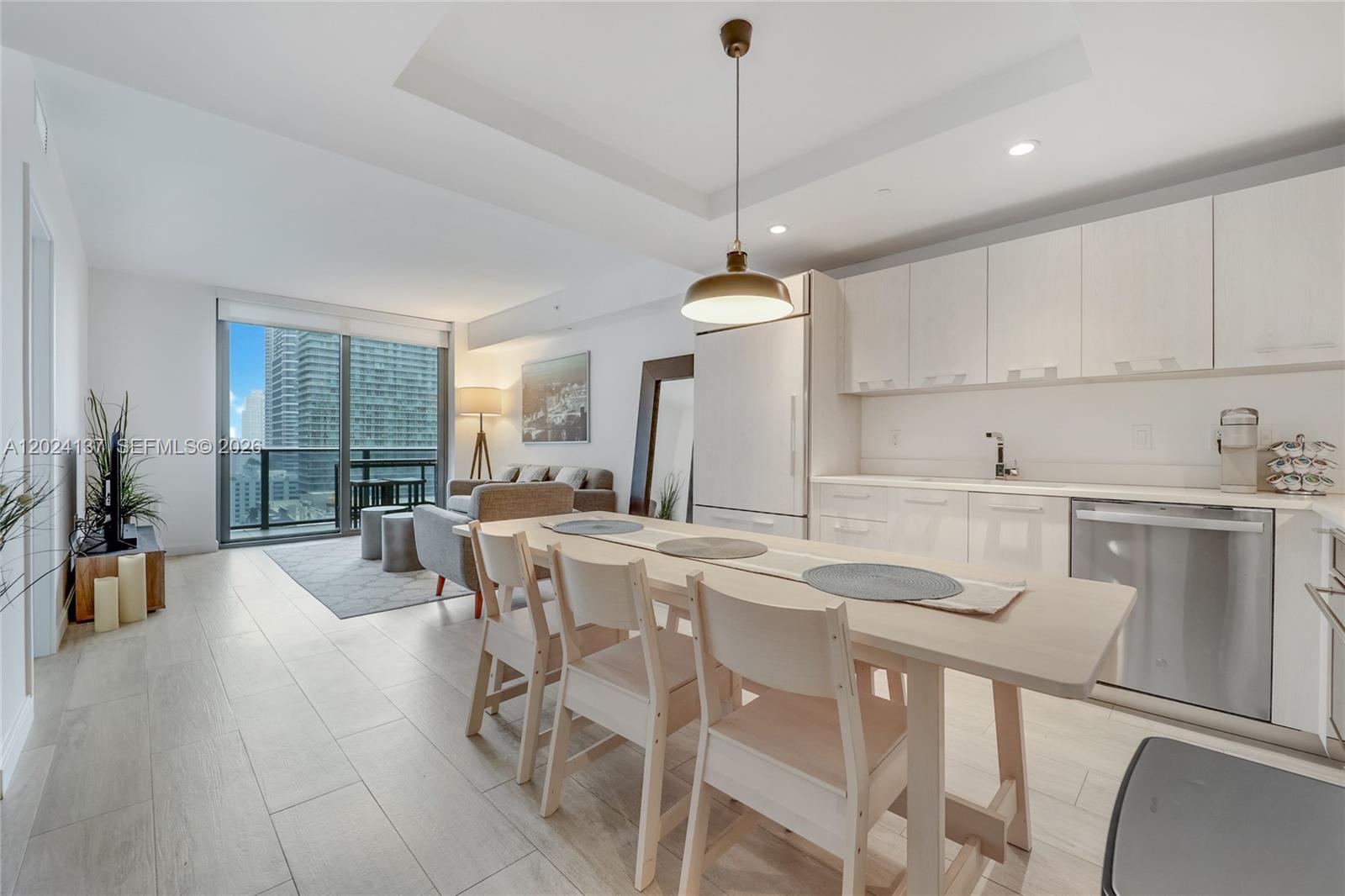 A modern open-concept kitchen and living area with light wood floors and a dining table — 45 SW 9 ST # 1905, Miami FL 33130, MIAMI, FL