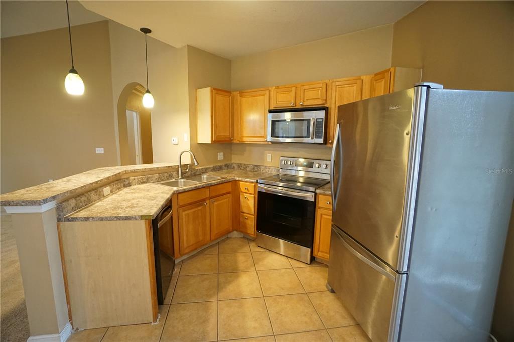 A kitchen with light wood cabinets, stainless steel appliances, and a breakfast bar — 18004 VILLA CREEK DRIVE, TAMPA, FL