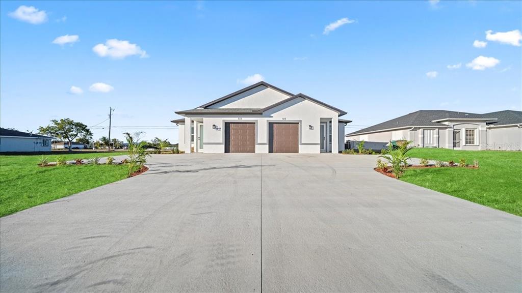 A front view of a duplex house with two garages and a large concrete driveway — 1318/1320 NE 16TH TERRACE, CAPE CORAL, FL