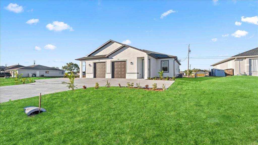 A single-story duplex with two garage doors and a concrete driveway under a blue sky — 1318/1320 NE 16TH TERRACE, CAPE CORAL, FL