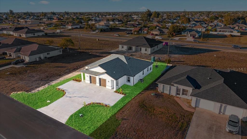 An aerial view shows a newly constructed single-family home with a concrete driveway and lawn — 1318/1320 NE 16TH TERRACE, CAPE CORAL, FL