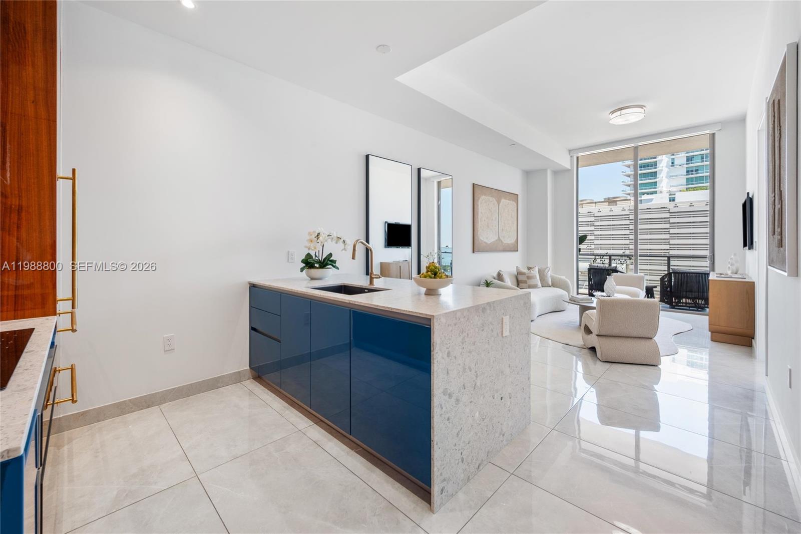 A modern kitchen island with blue cabinets and stone countertops sits in an open-plan living area — 2655 S Bayshore Dr # 1608, Miami FL 33133, MIAMI, FL