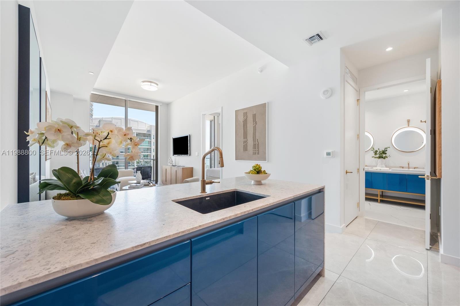 A kitchen island with a dark sink and blue cabinets sits before a living area — 2655 S Bayshore Dr # 1608, Miami FL 33133, MIAMI, FL
