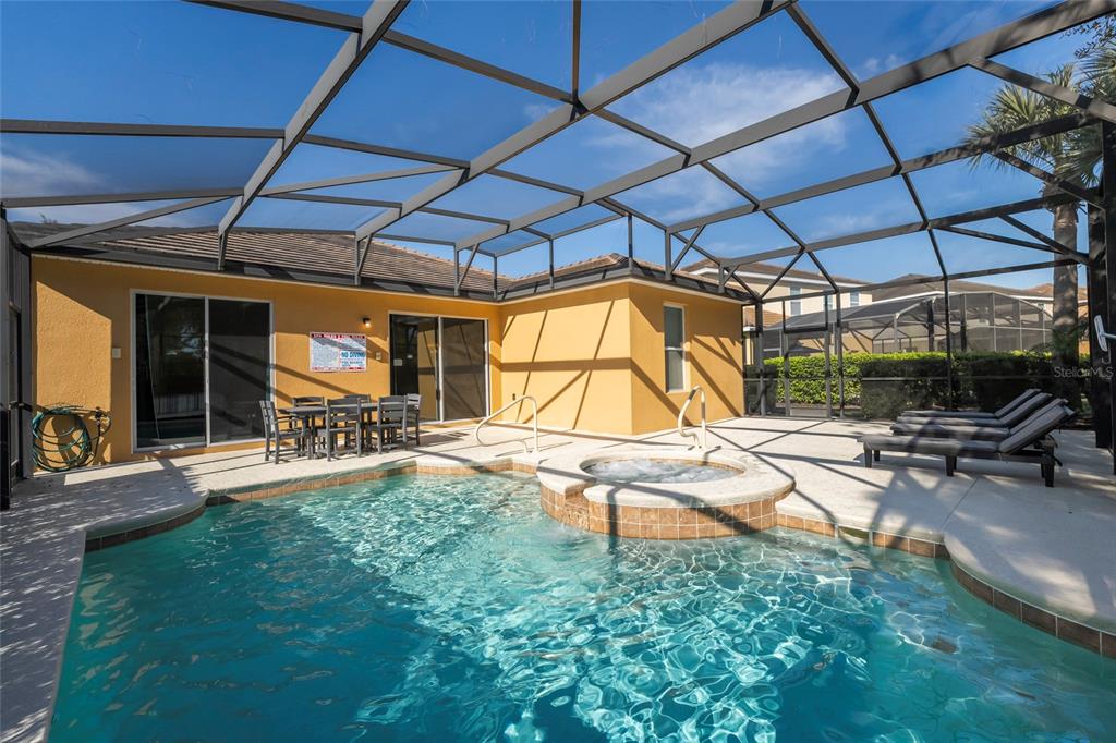 A screened-in patio features a swimming pool, a raised spa, and outdoor dining furniture — 5145 OAKBOURNE AVENUE, DAVENPORT, FL