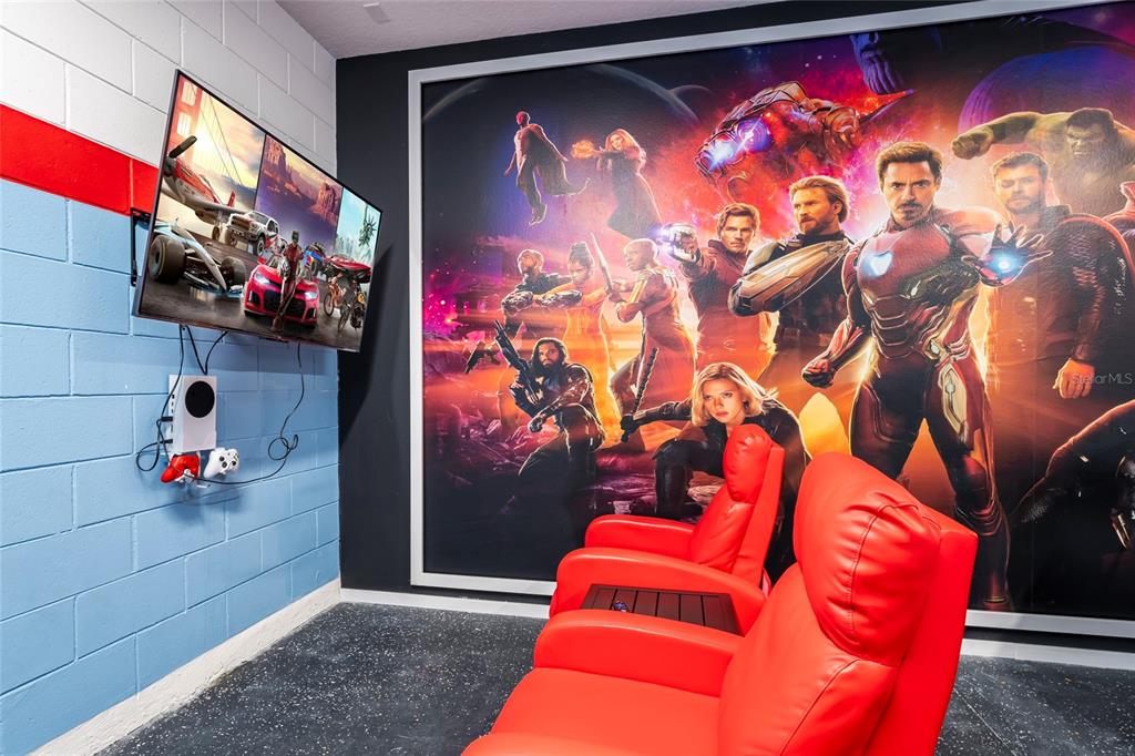 A home theater room features red leather recliners, a wall-mounted television, and a Marvel mural — 5145 OAKBOURNE AVENUE, DAVENPORT, FL