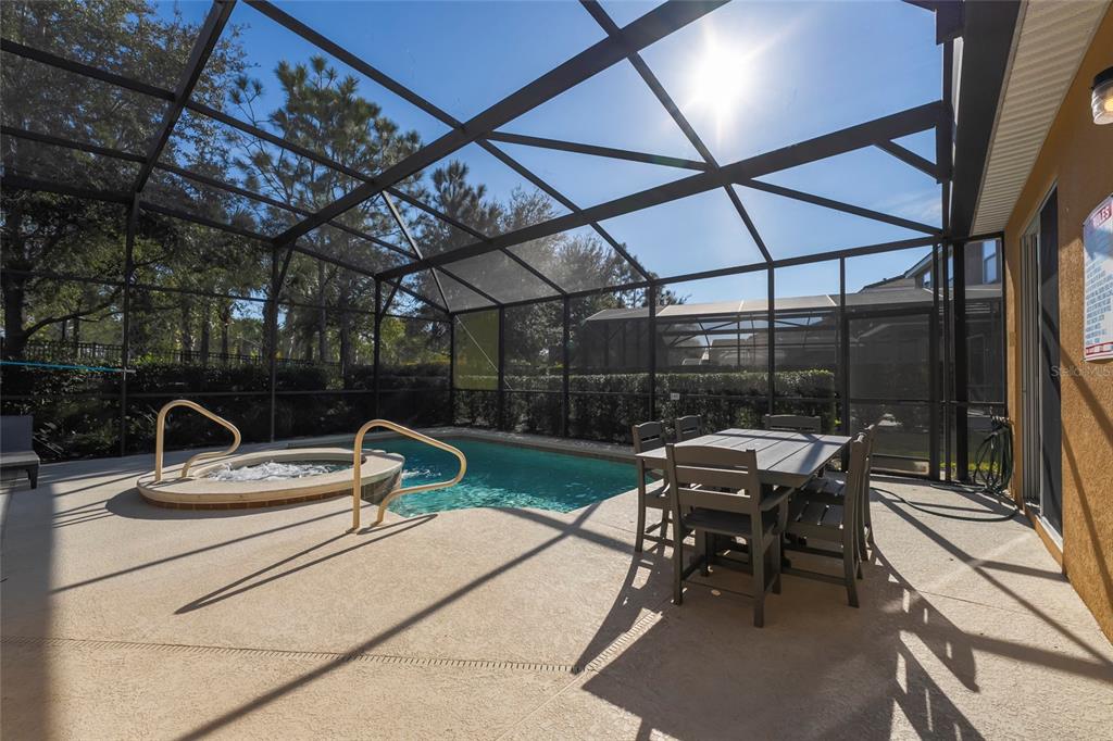 A screened-in patio features a swimming pool, a hot tub, and a dining set — 5145 OAKBOURNE AVENUE, DAVENPORT, FL