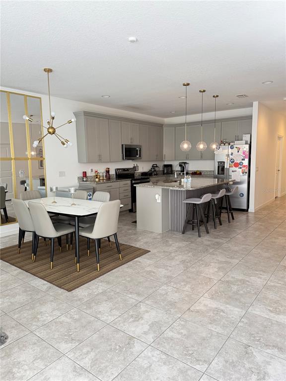 A kitchen and dining area feature gray cabinetry, a granite island, and tile flooring — 11102 HANLON TERRACE ALLEY, WINTER GARDEN, FL