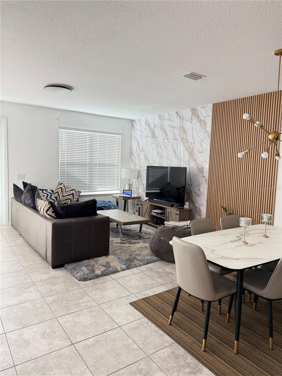 A living and dining area features tile floors, a marble accent wall, and wood slats — 11102 HANLON TERRACE ALLEY, WINTER GARDEN, FL