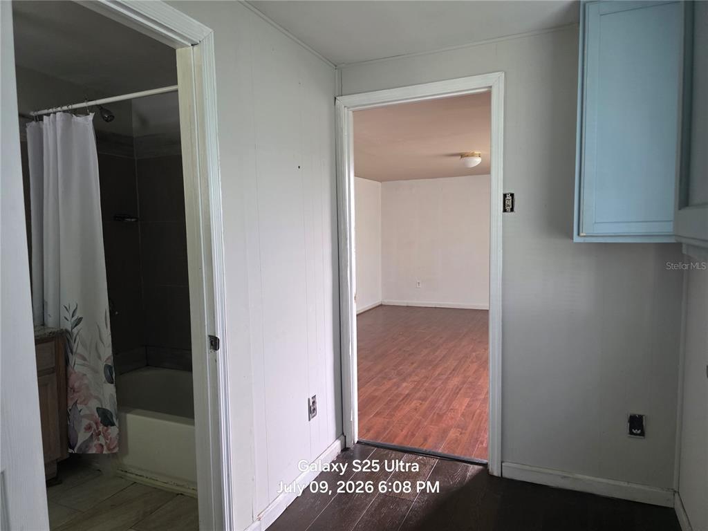 A view from a kitchen looking into a bathroom and an adjacent room with flooring — 2926 VOUSDEN LANE, LAKELAND, FL