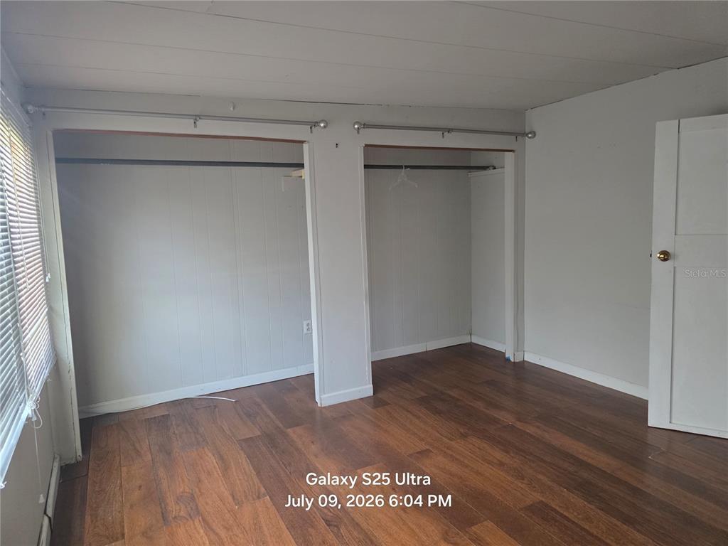 A room with wood-look flooring, light gray walls, and two open closet spaces — 2926 VOUSDEN LANE, LAKELAND, FL