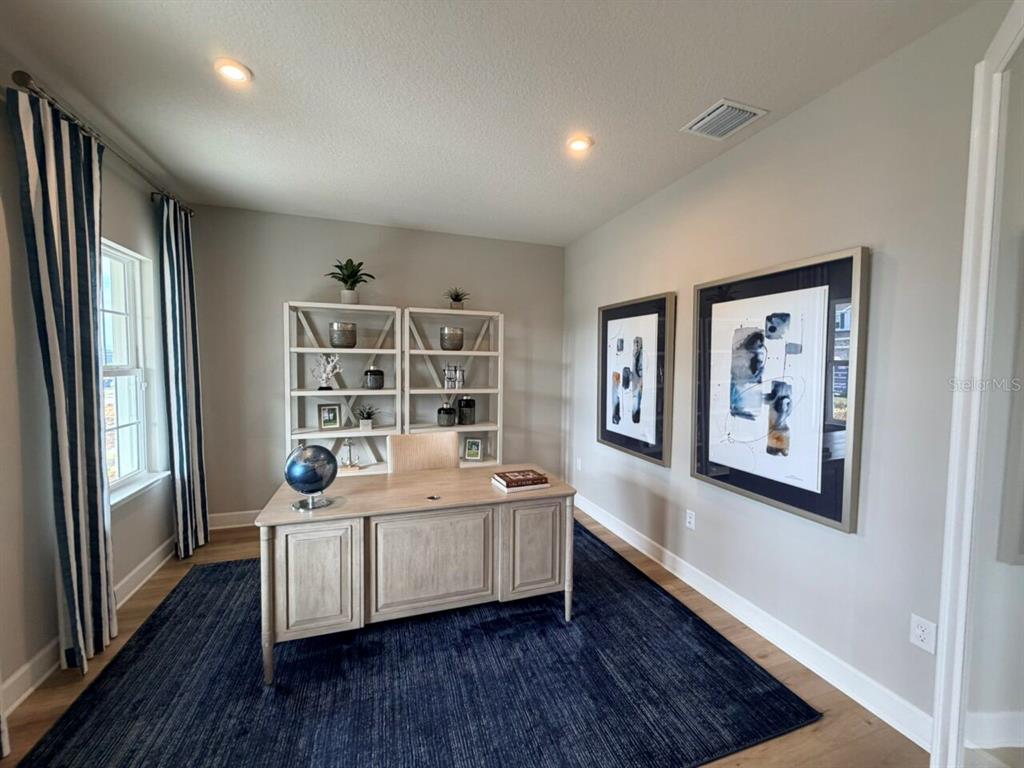 A room with light gray walls, wood-look flooring, a blue rug, and striped curtains — 1234 WHISPERING LANE, MINNEOLA, FL
