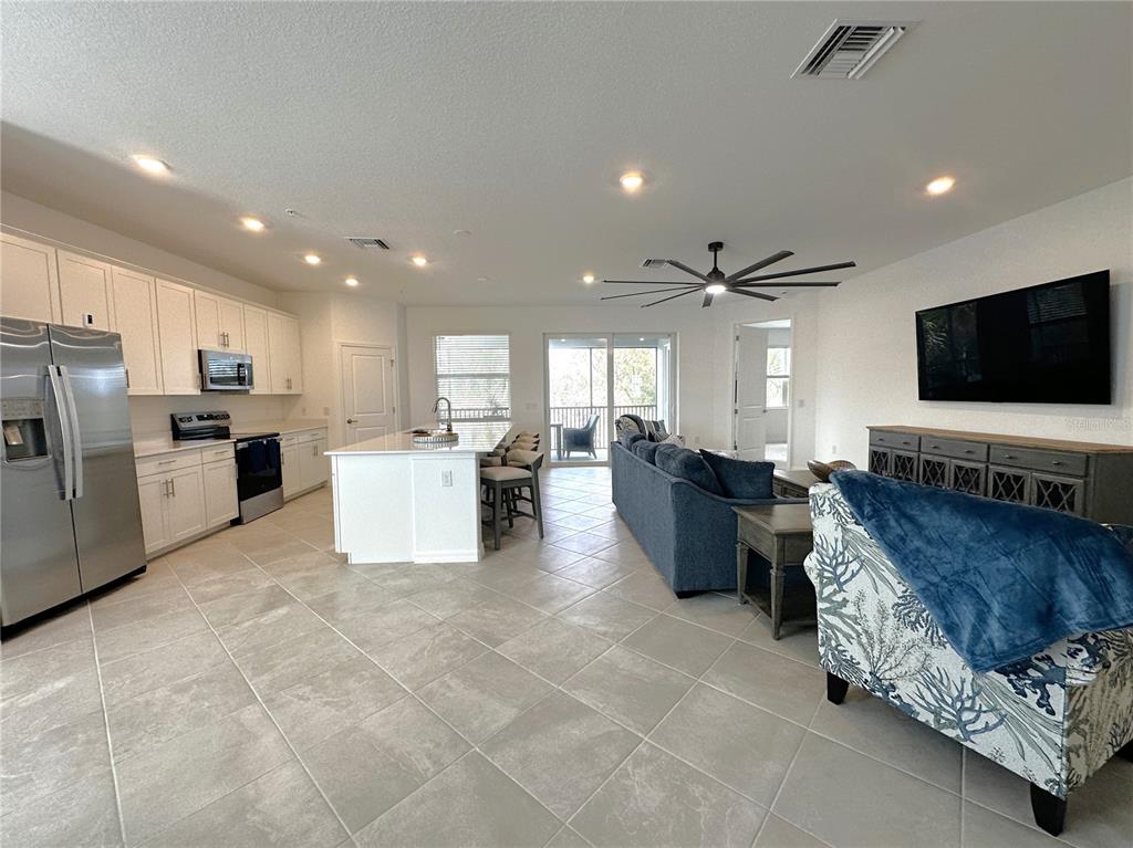 An open-concept kitchen and living area features white cabinetry, a kitchen island, and tile flooring — 14185 POPPY FIELD LOOP UNIT 5421, PUNTA GORDA, FL
