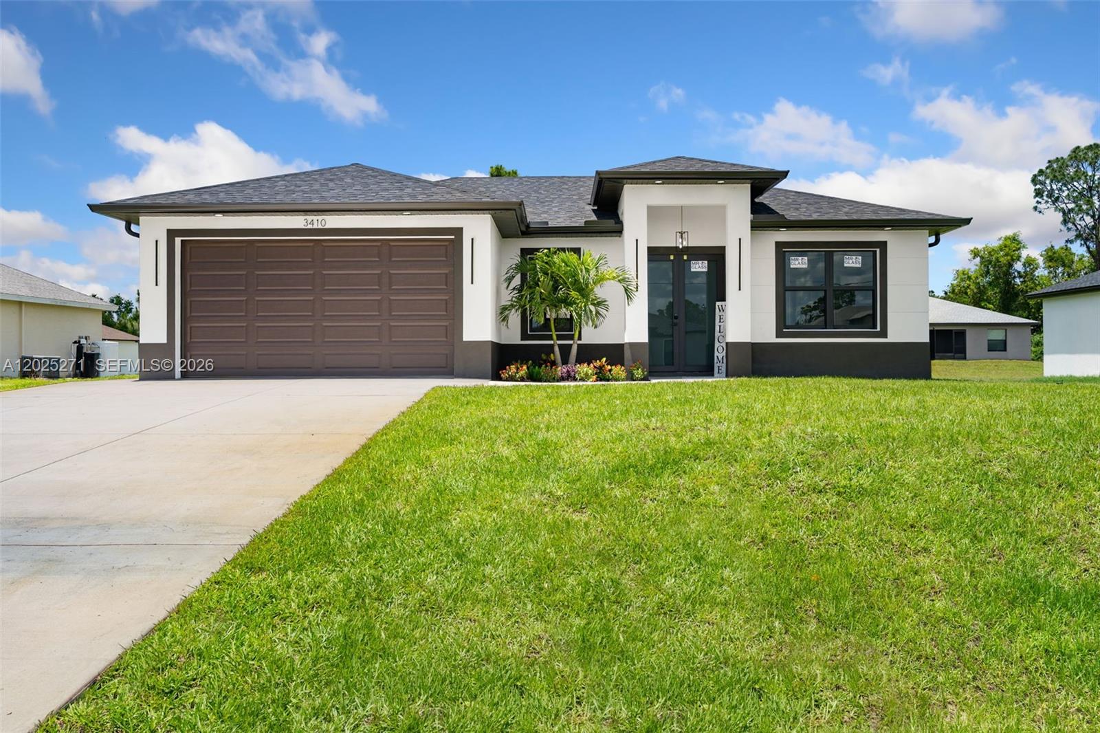 A single-story house with a two-car garage, white stucco walls, and a dark shingled roof — LEHIGH ACRES, FL