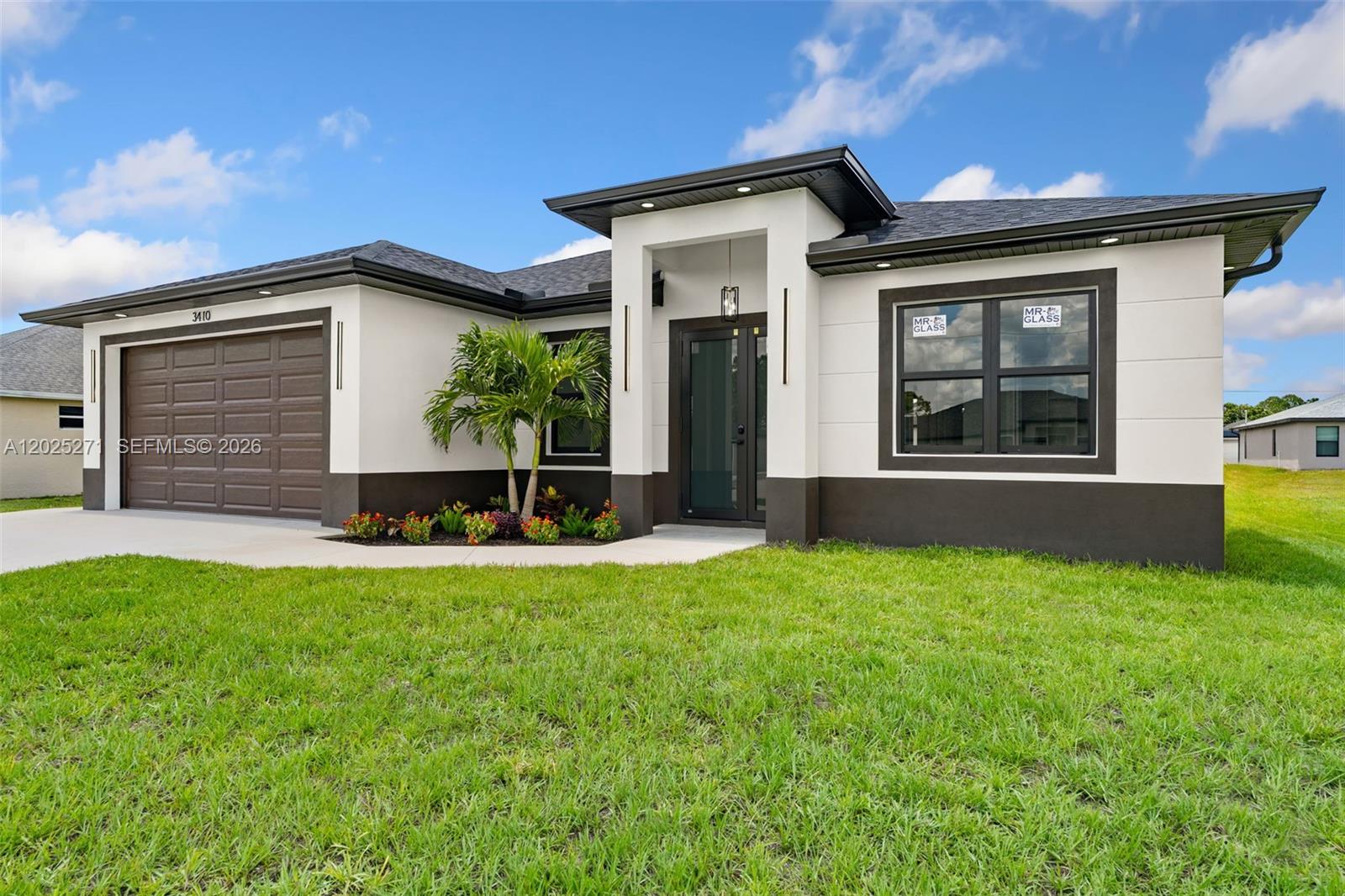 A modern single-story house features a white stucco exterior, dark trim, and a two-car garage — LEHIGH ACRES, FL