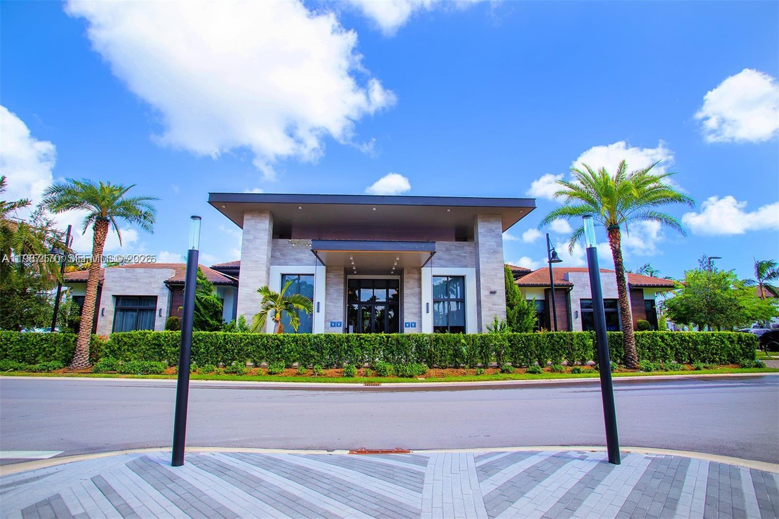 A modern clubhouse exterior features a stone facade, a flat roof, and palm trees — 8167 NW 41st St # 308, Doral FL 33166, DORAL, FL